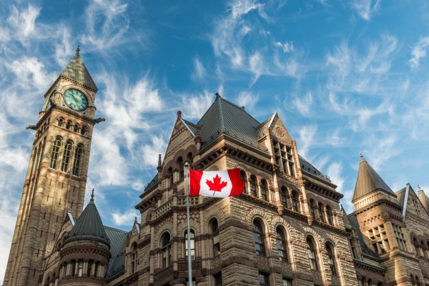 The Canadian flag flies before the Old City Hall in Toronto, Canada