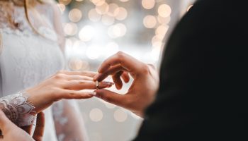 man placing wedding ring on woman's hand