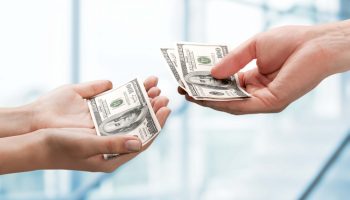 person giving 100 dollar bills to another person. allowance