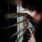 Fearful battered woman peeking through the blinds to see if her husband is home