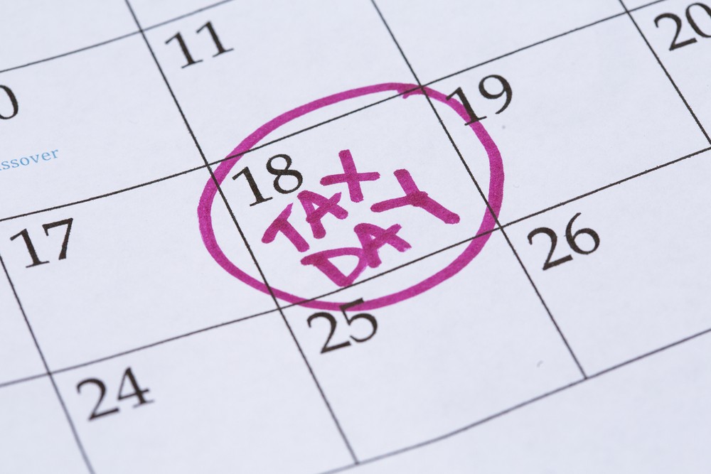 An April monthly calendar with the 18th circled with the words Tax Day written in the circle in a bright pink marker