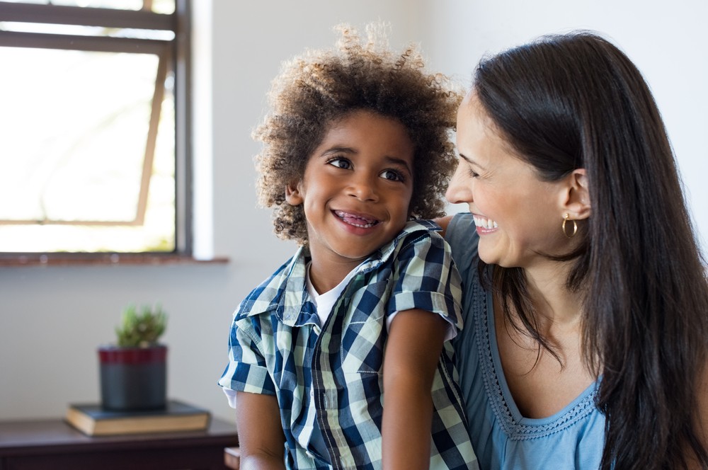 Close up face of latin woman playing with her african son. adoption concept