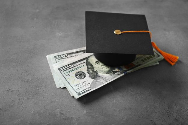 Graduation hat and dollar banknotes on table. Tuition fees concept