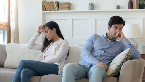 A couple sitting on a couch looking very stressed after an argument. Call a divorce lawyer in Howard County.