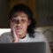 Concerned woman with curly hair resting her face on one hand, looking at a laptop screen in a dimly lit kitchen. what can be used against you in a custody battle