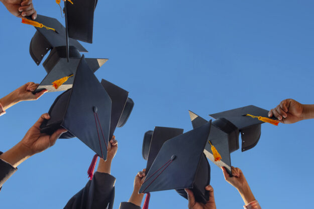 The students holding a shot of graduation cap by their hand in a bright sky during ceremony success graduates at the University, Concept of Successful Education in Hight School,Congratulated Degree High school graduates holding up their graduation caps - Does child support end at 18 or high school graduation in Maryland?